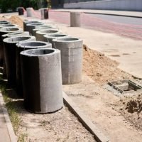 Laying concrete manholes and drain pipes for stormwater system. Connecting a trench drain to a concrete manhole structure at construction site. Construct stormwater and underground utilities. High quality photo