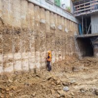 Construction worker checking pile retaining wall